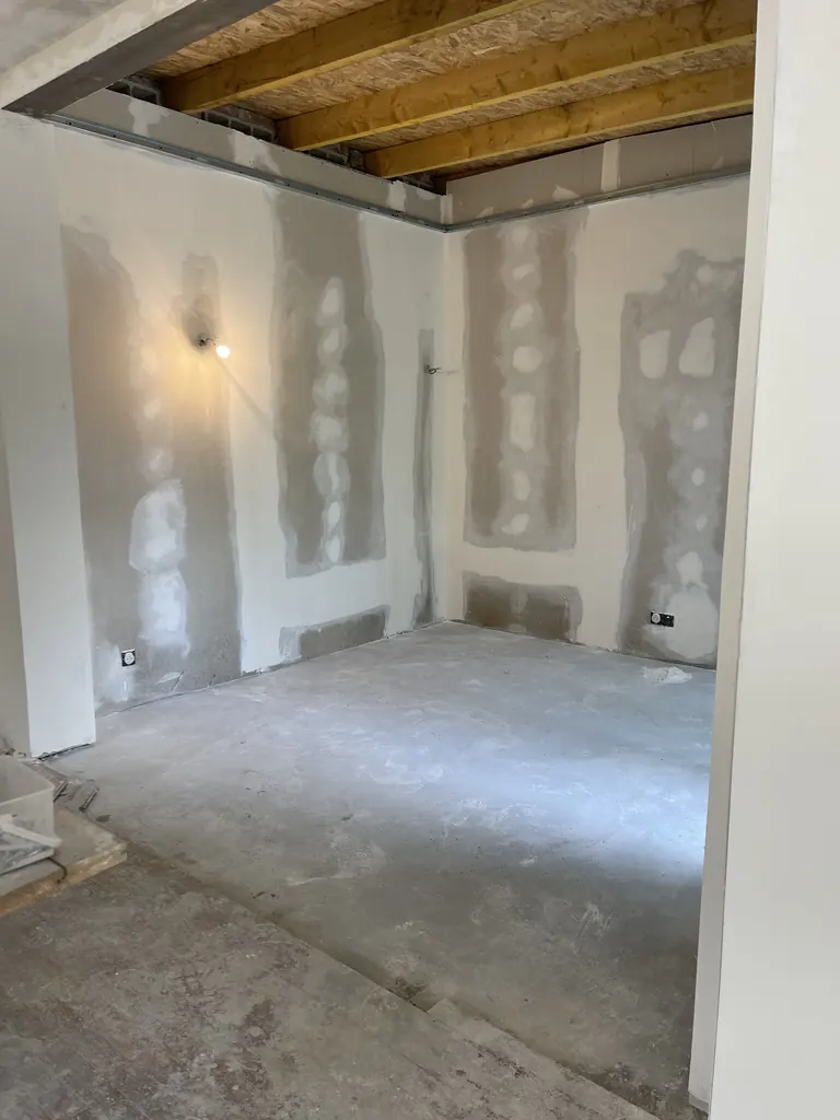 Cloisons en plaques de plâtre en cours de finition sous un solivage bois apparent