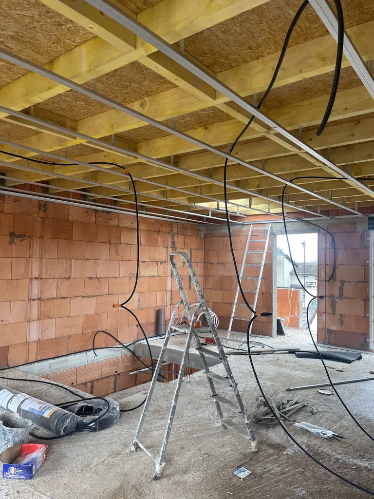 Chantier intérieur avec murs en briques, solivage bois et réseaux en attente