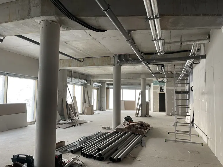 Plateau de bâtiment en travaux avec poteaux béton et réseaux techniques apparents