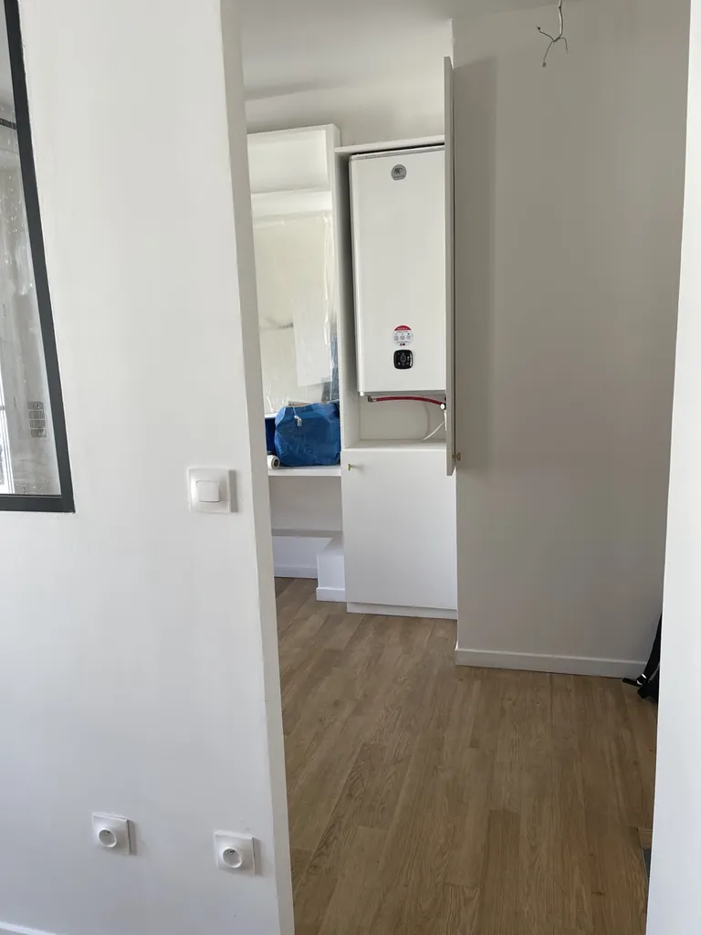 Placard blanc ouvert contenant un chauffe-eau dans un espace en cours de finition