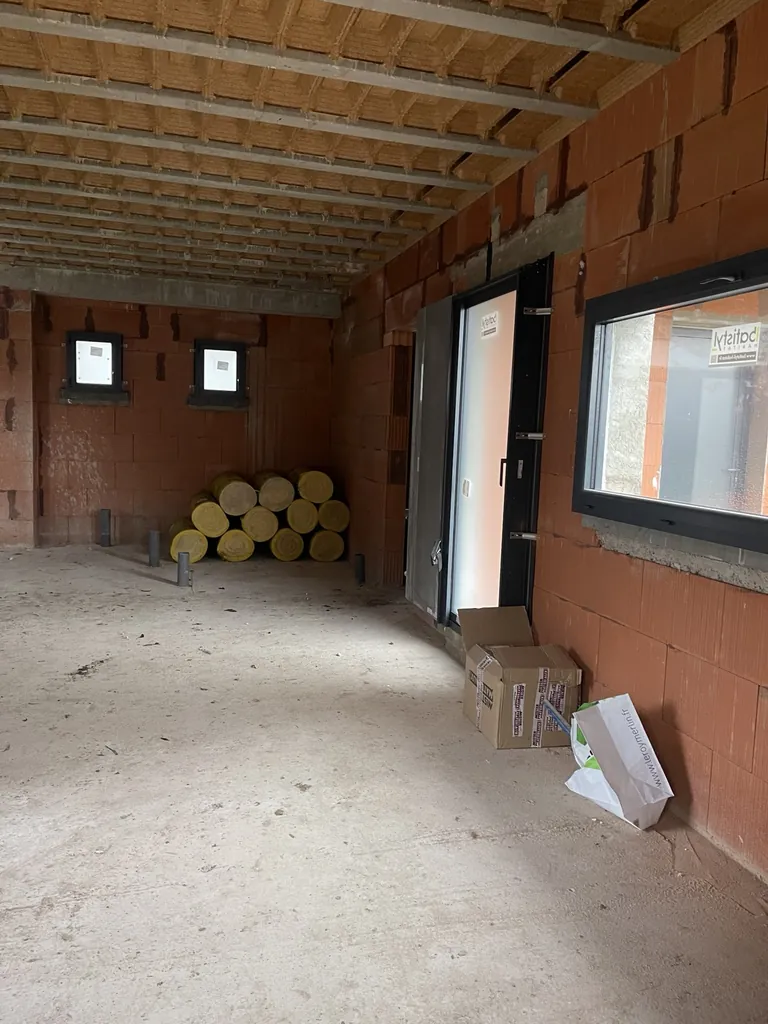 Pièce en briques avec porte, fenêtres posées et rouleaux d’isolant stockés pour les travaux