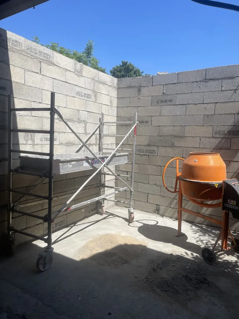 Murs en parpaings sur un chantier avec échafaudage mobile et bétonnière
