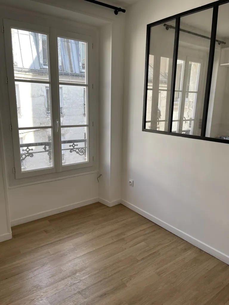 Pièce avec verrière intérieure noire, fenêtre blanche et sol aspect bois